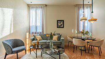 A modern living room with a grey sofa, a round coffee table, and a dining area with a table and chairs.