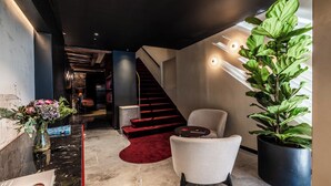 A modern lobby with a marble reception desk, a red carpet, a staircase, and a large potted plant. - Palazzo Rota Luxury Apartments (Venice)