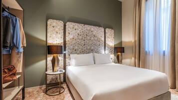 Une chambre d’hôtel avec un grand lit, une armoire, une petite table avec une lampe et une vue sur l’extérieur par la fenêtre.