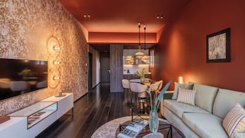 A modern living room with a flat-screen TV, a sofa, and a dining area with a table and chairs.