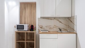 Une cuisine compacte équipée d’un four à micro-ondes, d’une machine à café et d’un petit évier.