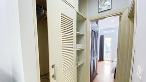 A hallway with a wardrobe, a clock, and a glimpse of a balcony. - Eco Nest Apartment & Stay (Hanoi)