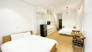 A modern hotel room with two beds, a desk, and a TV. - Eco Nest Apartment & Stay (Hanoi)