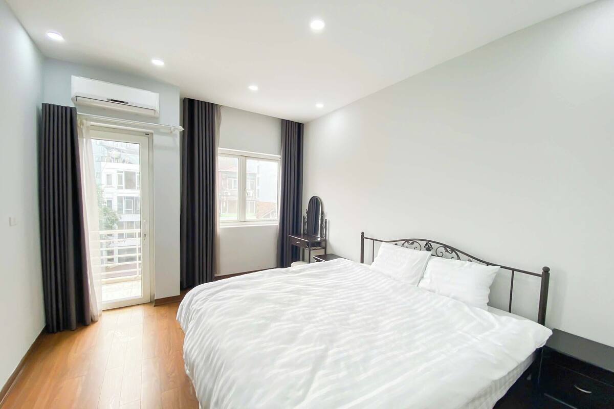 A bedroom with a large bed, a dresser, a chair, and an air conditioning unit.
