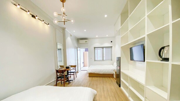 A modern hotel room with two beds, a dining area, and built-in storage. - Eco Nest Apartment & Stay (Hanoi)