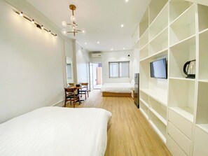 Et moderne hotelværelse med to senge, et spiseområde og indbyggede opbevaringsløsninger.