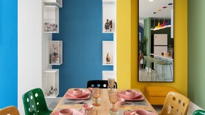 Een eetgedeelte met een houten tafel voor vier personen, omringd door kleurrijke stoelen.