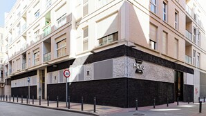 A multi-story building with a black and beige facade, a '30' speed limit sign, and a 'HEY U' sign indicating apartments. - Apartamentos HEY U (Murcia)