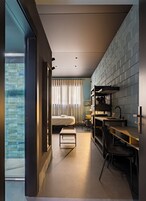 Una habitación de hotel moderna con una cama, una pequeña mesa, un escritorio y una kitchenette.
