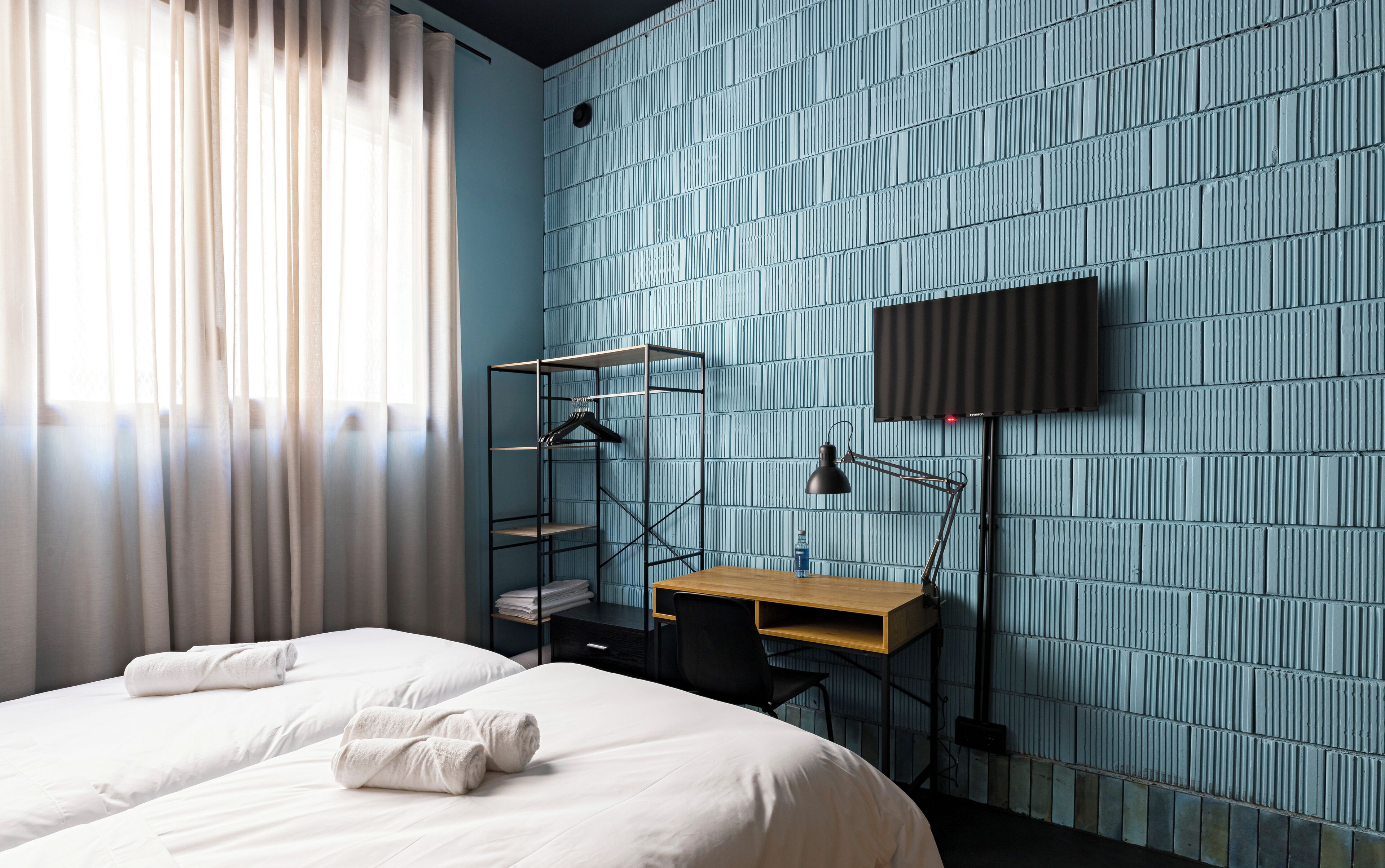 Een hotelkamer met een bed, een bureau, een stoel, een televisie en een kledingkast.