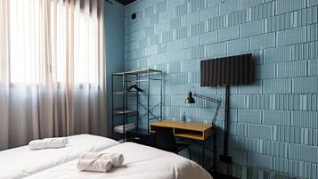 Een hotelkamer met een bed, een bureau, een stoel, een televisie en een kledingkast.