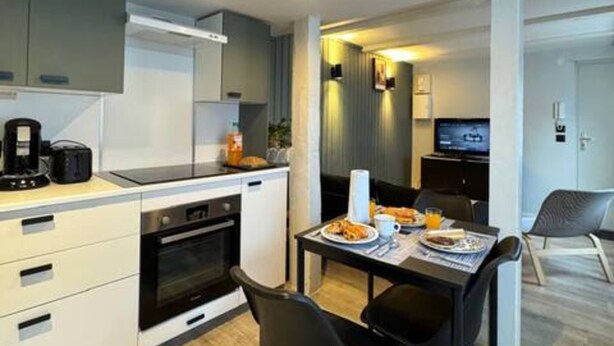A modern kitchen with a dining area, featuring a built-in oven, a coffee maker, and a dining table with chairs. - ConfortDream your haven of peace in Mulhouse (Mulhouse)
