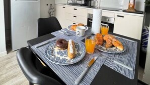 A compact kitchen with a refrigerator, microwave, and a dining area with a table set for breakfast. - ConfortDream your haven of peace in Mulhouse (Mulhouse)