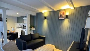 A modern living room with a black sofa, a wooden coffee table, and a black TV stand. - ConfortDream your haven of peace in Mulhouse (Mulhouse)