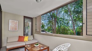 A balcony with a sofa, a white chair, and a wooden table.