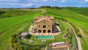 Une villa en pierre dotée d’une piscine, entourée de champs verdoyants et bordée d’un sentier sinueux.