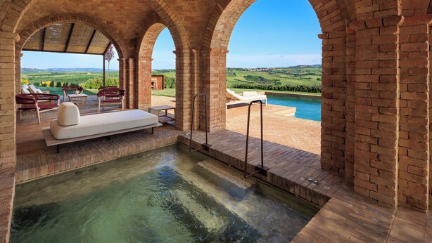 Un espace spa doté d’une piscine, de chaises longues et offrant une vue sur la campagne.