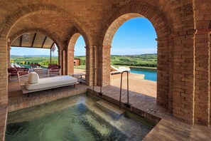 Un espace spa doté d’une piscine, de chaises longues et offrant une vue sur la campagne.