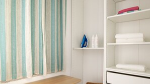 A bathroom with a wooden bench, a basket, and a white storage unit with shelves. - Villetta Otis by Wonderful Italy (San Teodoro)