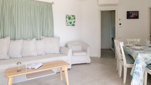 A modern living room with a sofa, armchair, dining table, and chairs. - Villetta Otis by Wonderful Italy (San Teodoro)