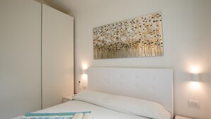 A neatly made bed with a book, a wall-mounted artwork, and bedside lamps. - Villetta Otis by Wonderful Italy (San Teodoro)