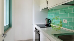 A narrow kitchen with white cabinets, a green tiled backsplash, and a stainless steel sink. - Villetta Otis by Wonderful Italy (San Teodoro)