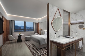 A modern hotel room with a bed, seating area, and a bathroom with a vanity and mirror. - Wanda Moments Xining Chengdong (Xining)
