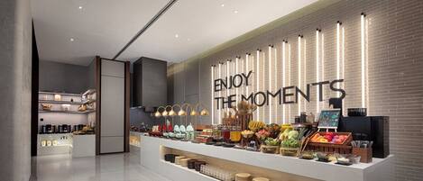 A modern kitchen area with a countertop displaying various food items and a wall with a sign that reads "ENJOY THE MOMENTS".
