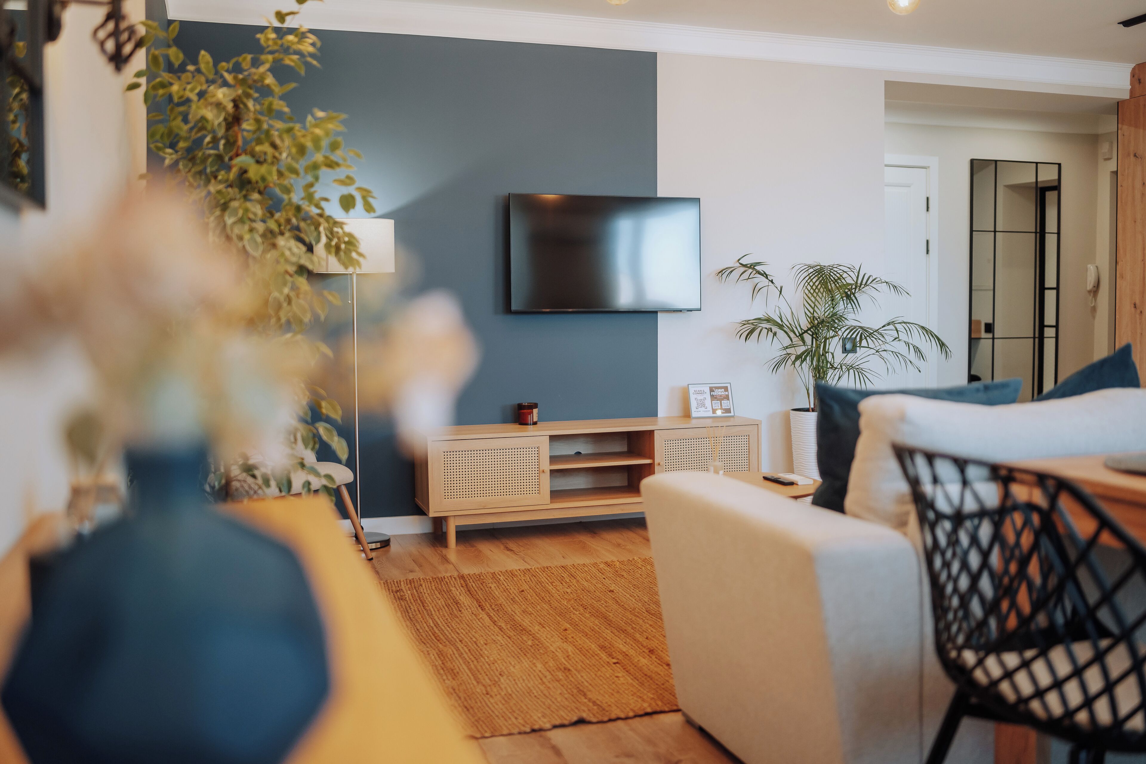 Una sala de estar moderna con una televisión de pantalla plana montada en la pared, un sofá, una mesa de centro y una planta en maceta.