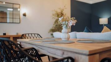 A dining area with a wooden table, black chairs, and a vase with flowers.