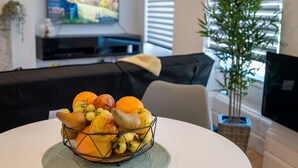 A dining table with a fruit basket, a sofa, a television, and a window with blinds. - 36 Queens Road Top Floor (Reading)