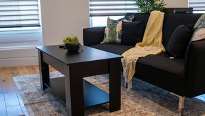 A modern living room with a black sofa, a dark wooden coffee table, and a patterned rug. - 36 Queens Road Top Floor (Reading)