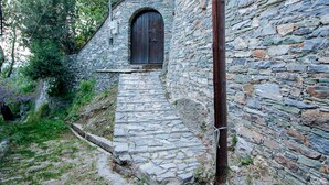 A stone staircase leading to a wooden door, surrounded by stone walls and greenery. - Secluded Cottage Guesthouse in the Mountains (Volos)