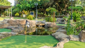 Un campo de mini golf con un estanque, rocas y césped artificial.