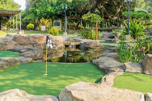 A miniature golf course with a pond, rocks, and artificial grass. - San Martinho Vila Azul (Praia do Bilene)