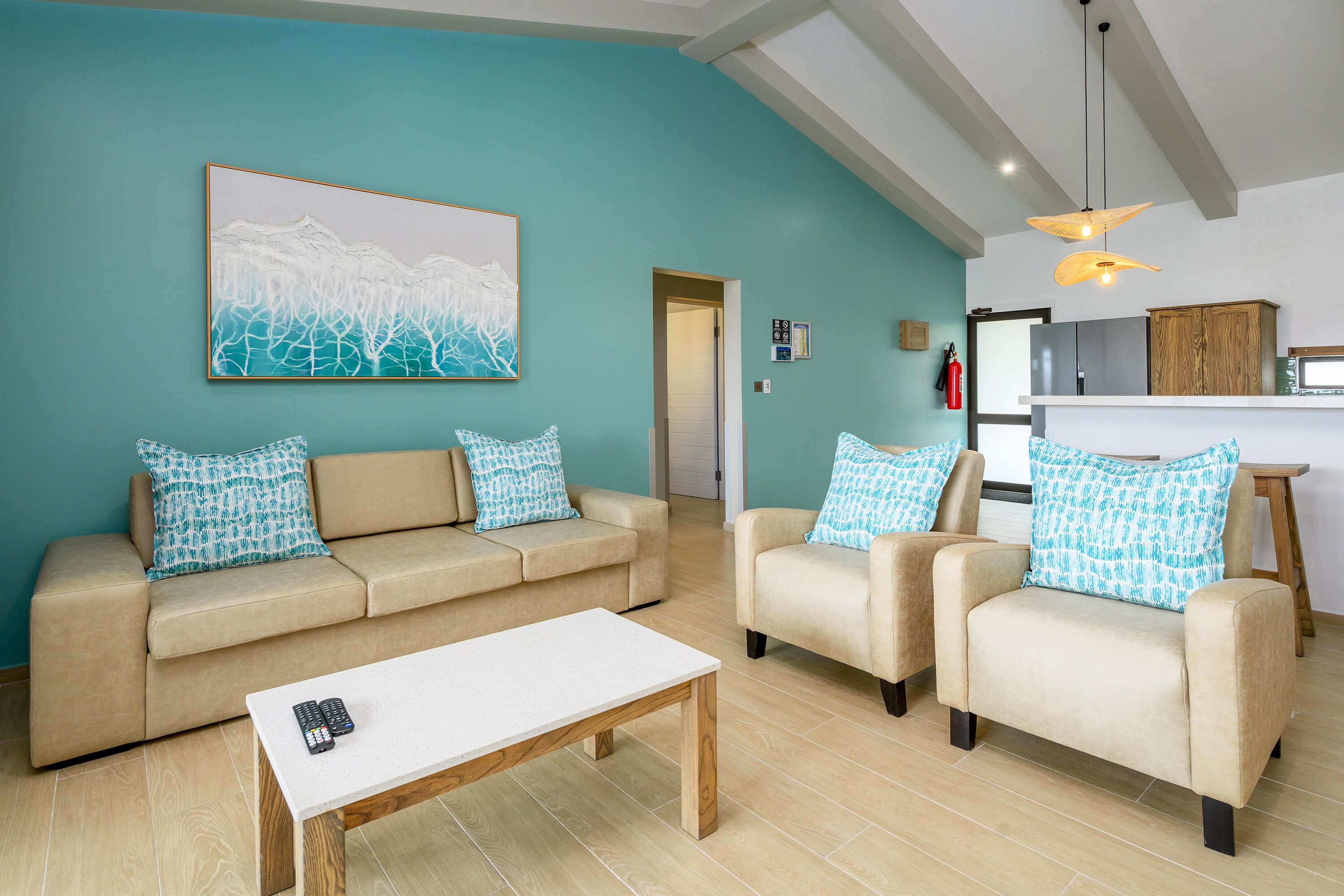 Una sala de estar con un sofá color beige, dos sillones, una mesa de centro y un cuadro en la pared.