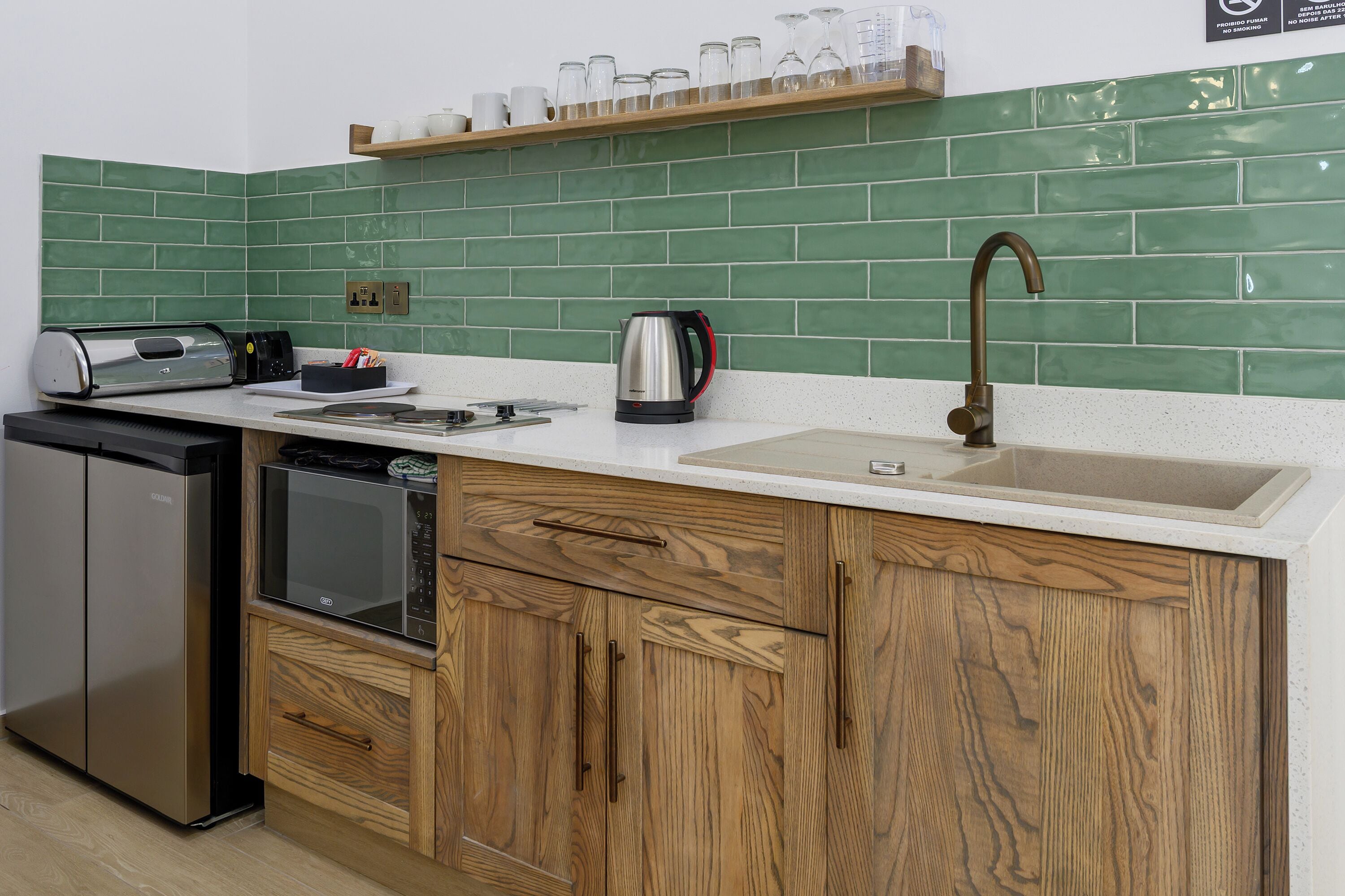 A kitchen with a dishwasher, a microwave, a kettle, and a sink.