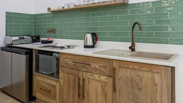 A kitchen with a dishwasher, a microwave, a kettle, and a sink.