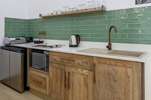 Una cocina equipada con lavavajillas, microondas, hervidor y pileta.