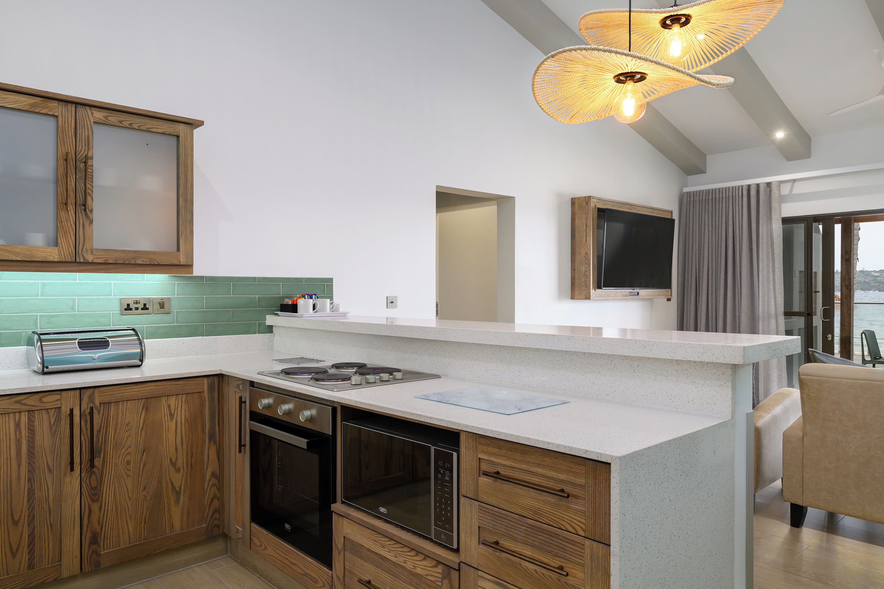 Une cuisine moderne avec des meubles en bois, un four encastré, une cuisinière à gaz et un grand îlot central doté d’un plan de travail en verre.