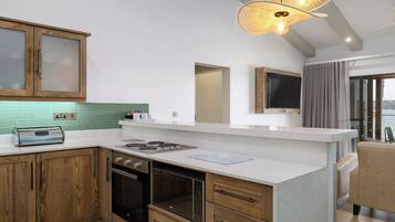 Une cuisine moderne avec des meubles en bois, un four encastré, une cuisinière à gaz et un grand îlot central doté d’un plan de travail en verre.