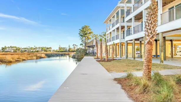 A waterfront walkway leading to a multi-story building with balconies.
