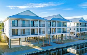 Une propriété située au bord de l’eau, comprenant plusieurs bâtiments à deux étages, chacun doté de balcons et d’un espace piscine.