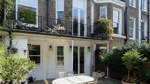 A townhouse with a patio area, outdoor seating, and potted plants. - The Kensington Townhouse, by Veeve (London)