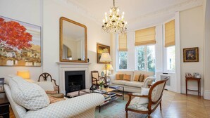A living room with a fireplace, a chandelier, and a large mirror. - The Kensington Townhouse, by Veeve (London)