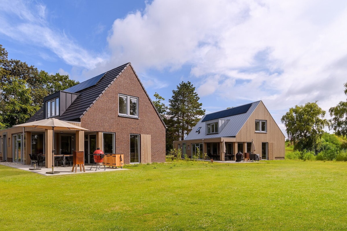 A modern two-story house with a covered patio and a barbecue area.