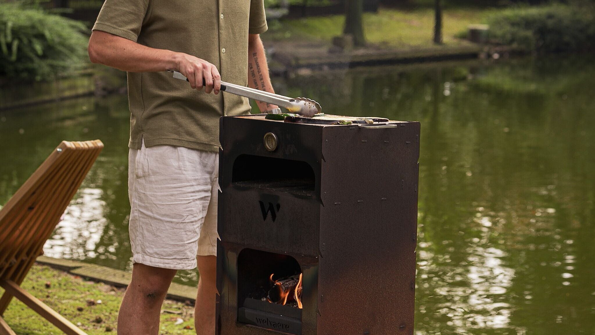 Une personne qui fait griller des aliments à l’extérieur, près d’une étendue d’eau.