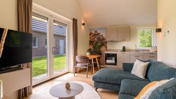A modern living room with a large flat-screen TV, a green sofa, and a small round table.