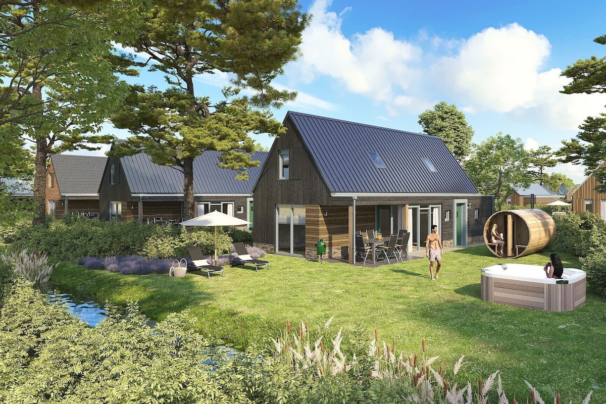A modern house with a large patio, a barrel sauna, and a pond.