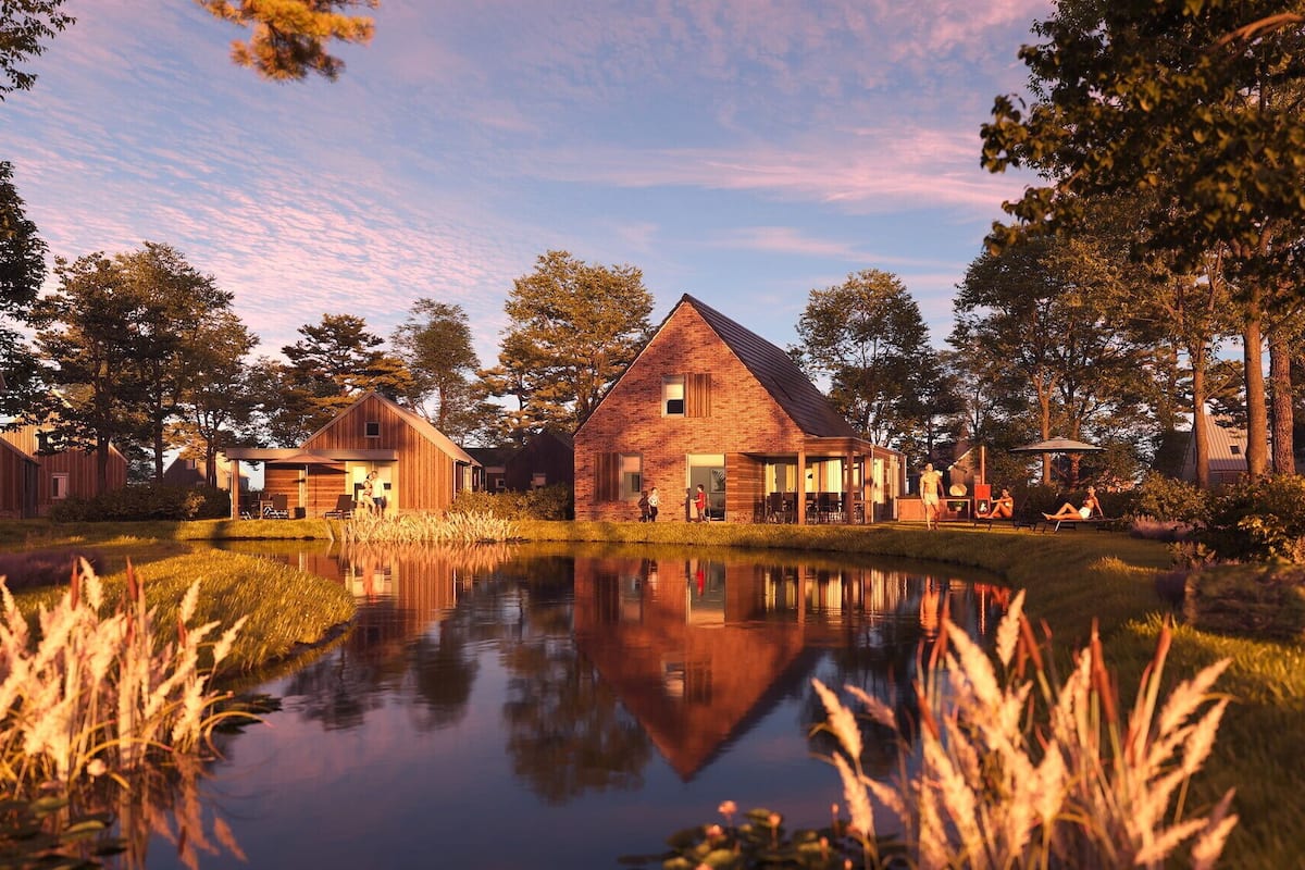 A rustic barn-style building with a pond in front, surrounded by trees and open grassy areas.